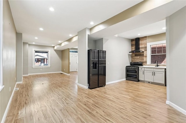 515 Peebles St, Wilkinsburg, PA 15221 - kitchen featuring black fridge with ice dispenser, range with two ovens, wall chimney exhaust hood, light wood finished floors, and recessed lighting