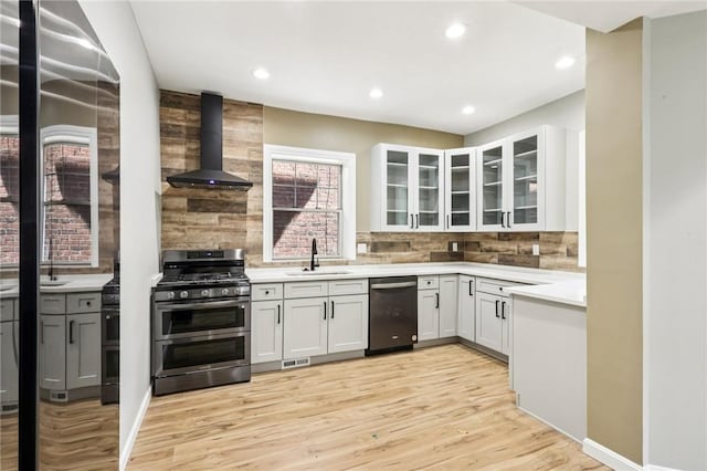 515 Peebles St, Wilkinsburg, PA 15221 - kitchen with appliances with stainless steel finishes, wall chimney range hood, decorative backsplash, light wood-style flooring, and light countertops