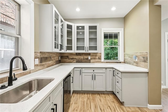 515 Peebles St, Wilkinsburg, PA 15221 - kitchen with light wood-style flooring, tasteful backsplash, black dishwasher, glass insert cabinets, and recessed lighting