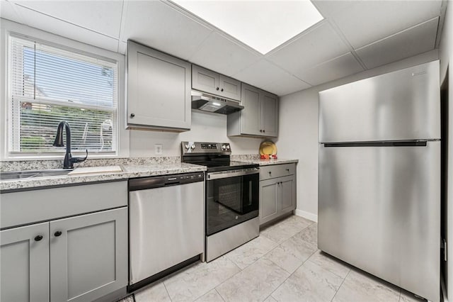 604 N 4th St, Jeannette, PA 15644 - kitchen with appliances with stainless steel finishes, gray cabinets, under cabinet range hood, a drop ceiling, and light marble finish flooring
