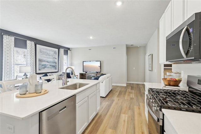3051 Audrey Dr, Hempfield Twp, PA 15601 - kitchen with appliances with stainless steel finishes, open floor plan, light wood-style flooring, white cabinets, and light countertops