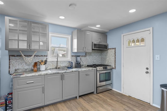 7129 Michigan Ave, Swissvale, PA 15218 - kitchen with appliances with stainless steel finishes, light wood-type flooring, decorative backsplash, gray cabinetry, and recessed lighting