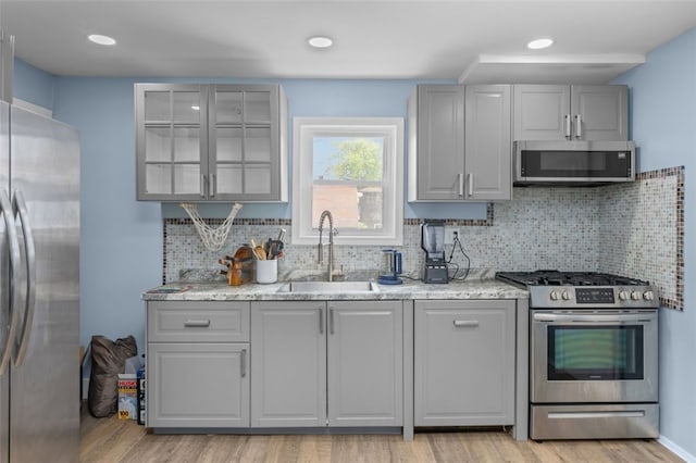 7129 Michigan Ave, Swissvale, PA 15218 - kitchen featuring stainless steel appliances, light wood-style floors, backsplash, gray cabinets, and light stone countertops