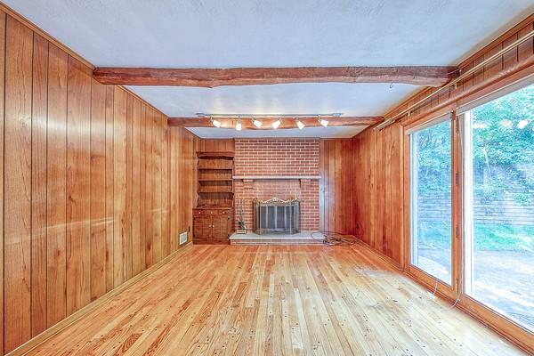 4517 W Brightview Ave, Whitehall, PA 15227 - unfurnished living room featuring wood walls, hardwood / wood-style flooring, beam ceiling, and a fireplace