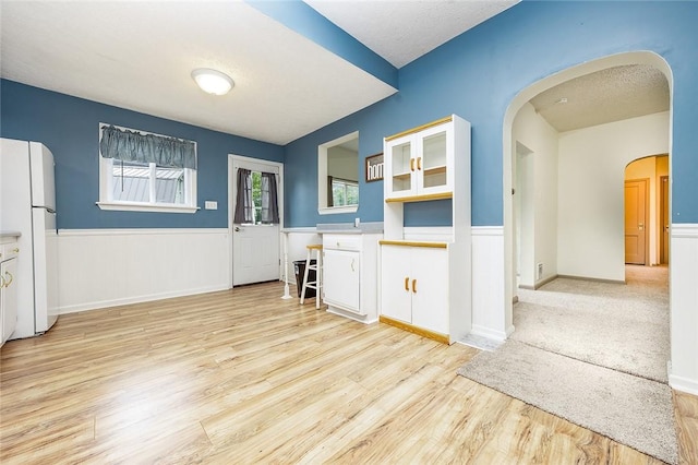 407 Hill St, Grove City Boro, PA 16127 - kitchen featuring freestanding refrigerator, arched walkways, light wood-style flooring, white cabinets, and glass insert cabinets