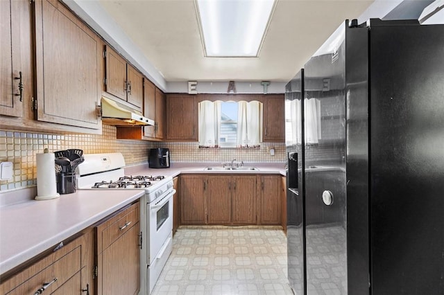 623 Rte 30, Findlay Twp, PA 15126 - kitchen with fridge with ice dispenser, white gas range oven, under cabinet range hood, light floors, and light countertops