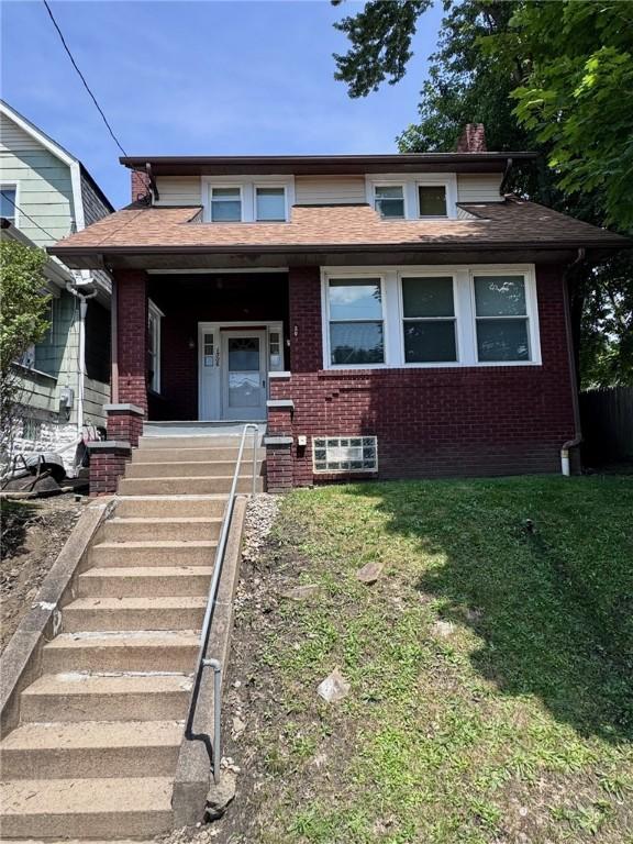 1506 Victoria Ave, New Kensington, PA 15068 - view of front facade with brick siding, a front lawn, roof with shingles, and stairs