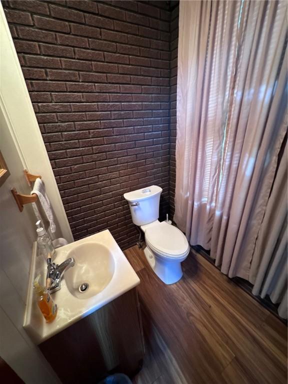 1506 Victoria Ave, New Kensington, PA 15068 - bathroom featuring brick wall, vanity, and wood finished floors