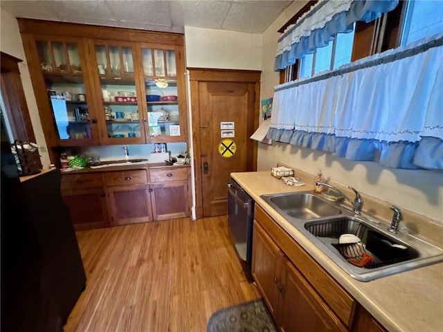 1506 Victoria Ave, New Kensington, PA 15068 - kitchen featuring dishwasher, light wood-style floors, light countertops, brown cabinets, and glass insert cabinets