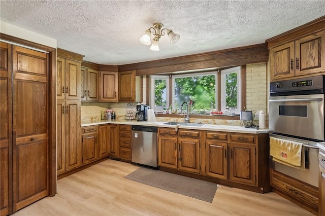 4296 Morefield Rd, Hermitage, PA 16148 - kitchen featuring appliances with stainless steel finishes, brown cabinetry, light wood-style flooring, a textured ceiling, and a warming drawer