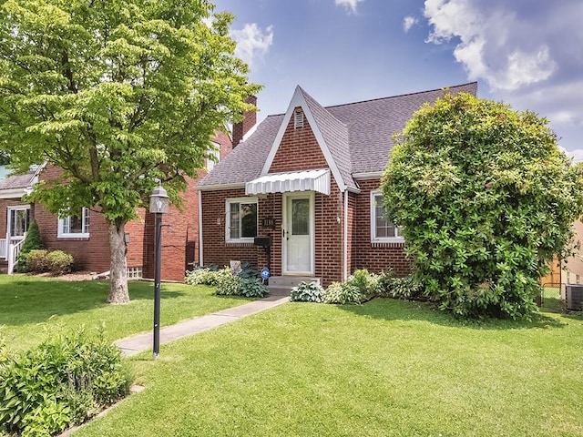 1138 Union Ave, Brackenridge, PA 15014 - tudor home featuring brick siding, roof with shingles, a front lawn, and a chimney