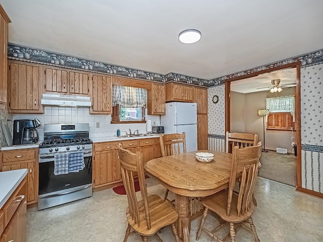 1138 Union Ave, Brackenridge, PA 15014 - kitchen with stainless steel range with gas cooktop, under cabinet range hood, freestanding refrigerator, light countertops, and brown cabinets