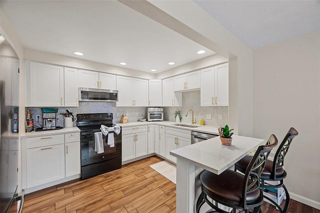 206 Little Hollow Dr, Aleppo, PA 15143 - kitchen with stainless steel appliances, light wood-type flooring, a breakfast bar area, light countertops, and white cabinetry