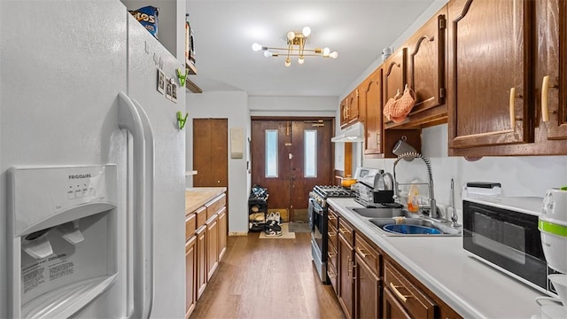117 Carroll St, Aliquippa, PA 15001 - kitchen featuring white fridge with ice dispenser, gas range, under cabinet range hood, wood finished floors, and light countertops