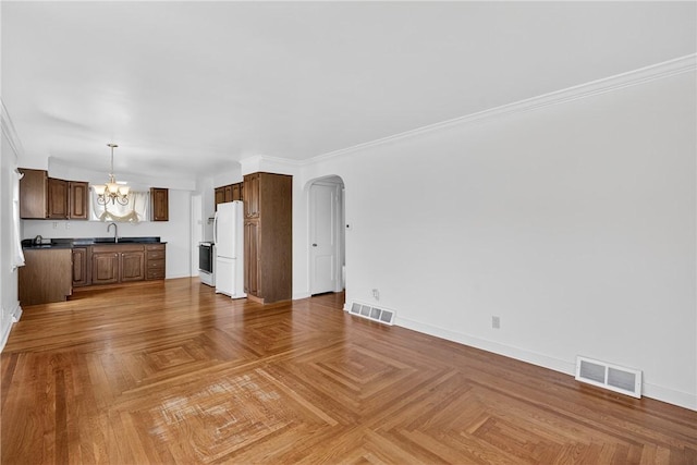17 Fremont Rd, Pa, PA 15022 - unfurnished living room featuring a chandelier, arched walkways, and crown molding