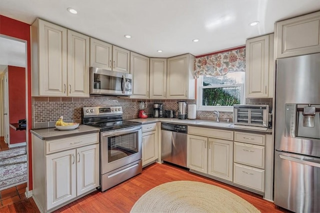 1230 Northwestern Dr, Monroeville, PA 15146 - kitchen with stainless steel appliances, cream cabinetry, backsplash, light wood-type flooring, and recessed lighting