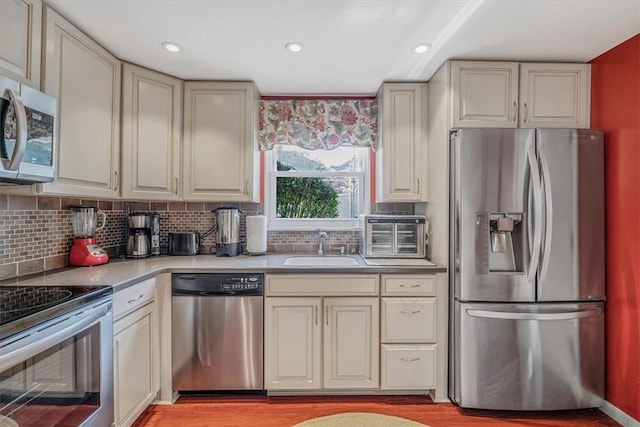 1230 Northwestern Dr, Monroeville, PA 15146 - kitchen featuring stainless steel appliances, tasteful backsplash, cream cabinetry, light wood-style floors, and recessed lighting