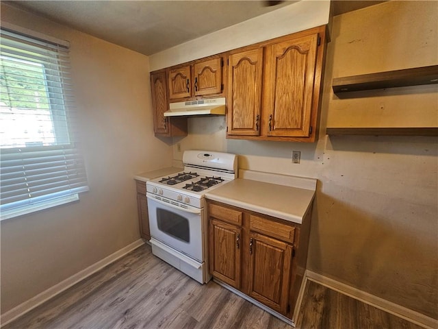 4235 Willow Ave, Castle Shannon, PA 15234 - kitchen featuring white gas range, under cabinet range hood, wood finished floors, and brown cabinetry