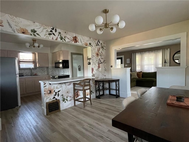1022 Dewey Ave, New Castle/3Rd, PA 16101 - kitchen with stainless steel appliances, a chandelier, light wood finished floors, backsplash, and a peninsula