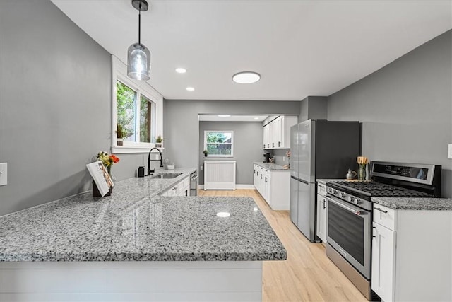 7032 Reynolds St, Point Breeze, PA 15208 - kitchen with appliances with stainless steel finishes, light wood-type flooring, light stone counters, white cabinets, and a peninsula