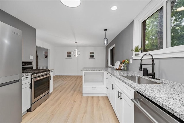 7032 Reynolds St, Point Breeze, PA 15208 - kitchen with stainless steel appliances, white cabinetry, light stone countertops, light wood finished floors, and decorative light fixtures
