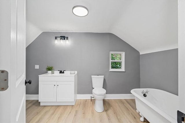 7032 Reynolds St, Point Breeze, PA 15208 - bathroom with a freestanding tub, wood finished floors, vaulted ceiling, and vanity