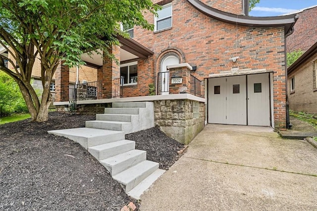 7032 Reynolds St, Point Breeze, PA 15208 - property entrance featuring a garage, brick siding, concrete driveway, and covered porch
