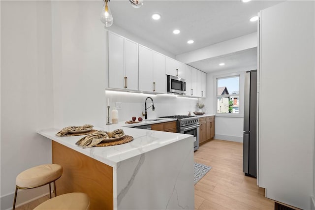 3246 Piedmont Ave, Dormont, PA 15216 - kitchen featuring stainless steel appliances, a peninsula, recessed lighting, light stone countertops, and light wood-style flooring