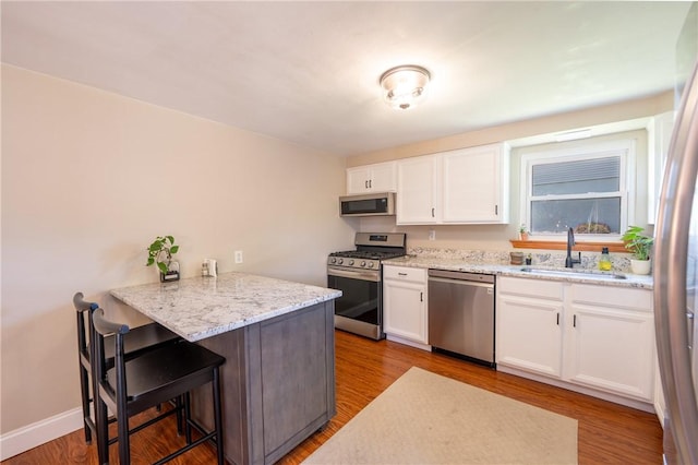 205 Eleanor Dr, Latrobe, PA 15650 - kitchen featuring appliances with stainless steel finishes, white cabinets, a kitchen breakfast bar, a peninsula, and light stone counters