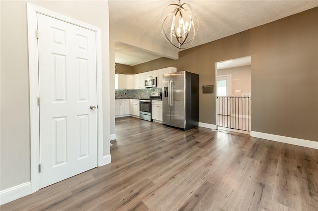 413 Spring St, Grove City Boro, PA 16127 - kitchen featuring appliances with stainless steel finishes, a chandelier, white cabinetry, dark wood-style flooring, and pendant lighting