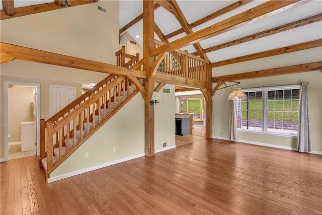 2161/2 Robin Hood Dr, Irwin, PA 15642 - unfurnished living room featuring beam ceiling, stairway, wood finished floors, and high vaulted ceiling