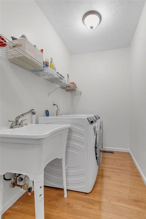 642 Water View Dr, Cranberry Twp, PA 16066 - laundry area with washer and clothes dryer, light wood-type flooring, and a textured ceiling