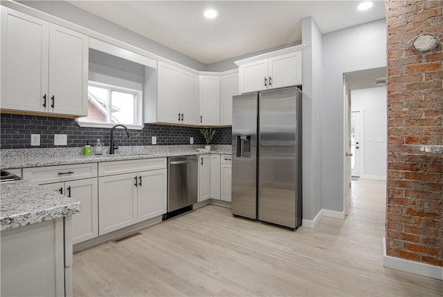 226 Main Street Ext, Callery Boro, PA 16024 - kitchen with appliances with stainless steel finishes, light wood-style flooring, decorative backsplash, light stone counters, and white cabinets