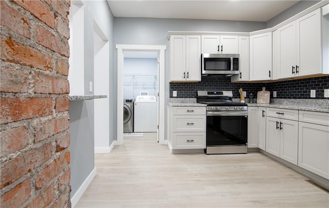 226 Main Street Ext, Callery Boro, PA 16024 - kitchen with appliances with stainless steel finishes, washer and dryer, light wood-style flooring, decorative backsplash, and white cabinetry