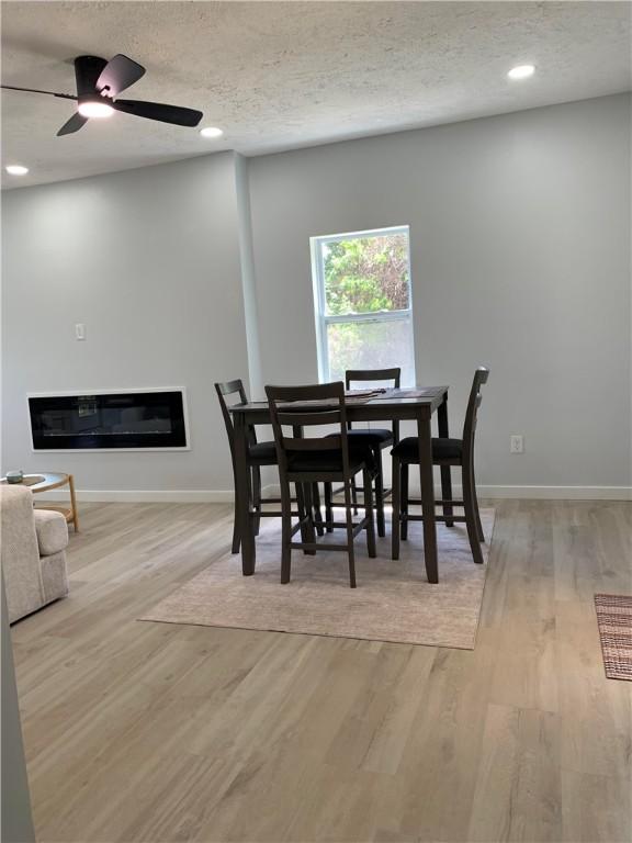 226 Main Street Ext, Callery Boro, PA 16024 - dining room featuring light wood-style floors, a glass covered fireplace, recessed lighting, a textured ceiling, and ceiling fan