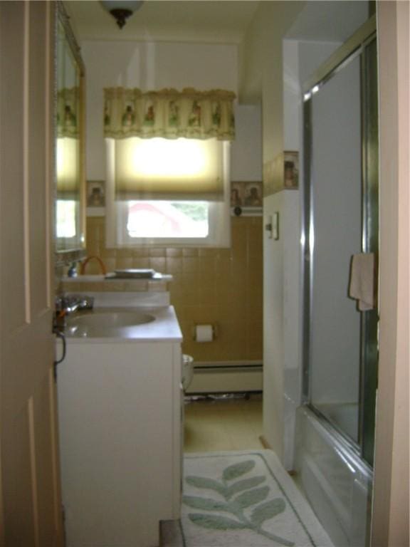 404 Scipio, Jamestown, PA 16134 - full bath with a baseboard radiator, tile walls, vanity, and bath / shower combo with glass door