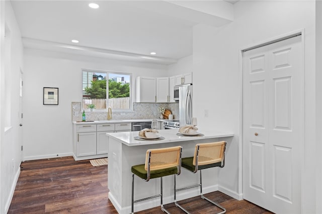 211 Taylor St, Bloomfield, PA 15224 - kitchen with decorative backsplash, white cabinets, dark wood-style flooring, a peninsula, and a breakfast bar