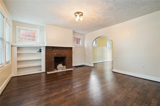 2072 Dartmore St, Overbrook, PA 15210 - unfurnished living room with a textured ceiling, arched walkways, wood finished floors, and a fireplace