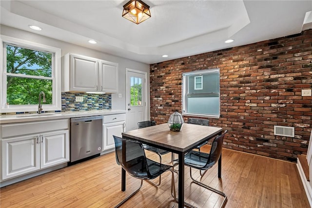312 Edith St, Mt Washington, PA 15211 - kitchen featuring stainless steel dishwasher, brick wall, light countertops, light wood-type flooring, and a raised ceiling