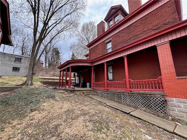 26 Carrick Ave, Carrick, PA 15210 - view of home's exterior with covered porch, brick siding, and a chimney