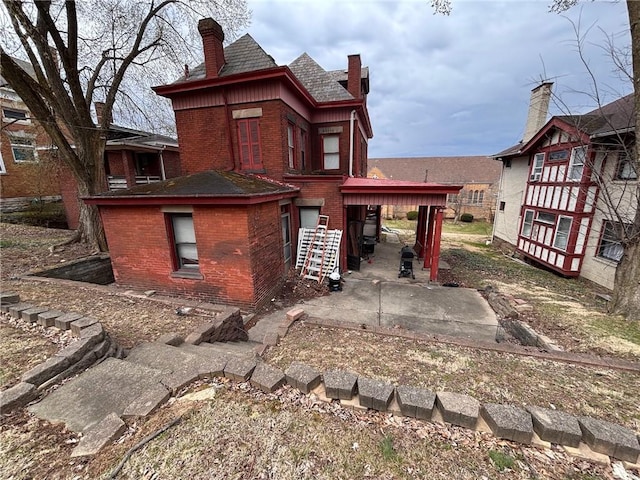 26 Carrick Ave, Carrick, PA 15210 - rear view of house featuring brick siding, a patio area, and a chimney