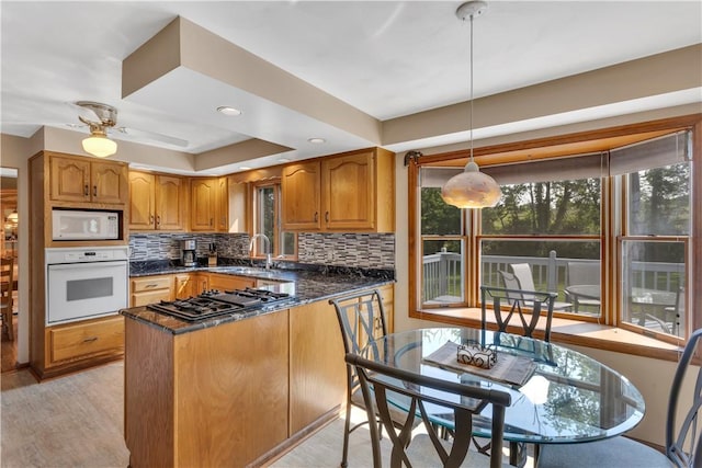 116 Rizzi Dr, Penn Twp Wml, PA 15642 - kitchen with white appliances, brown cabinets, tasteful backsplash, light wood finished floors, and decorative light fixtures