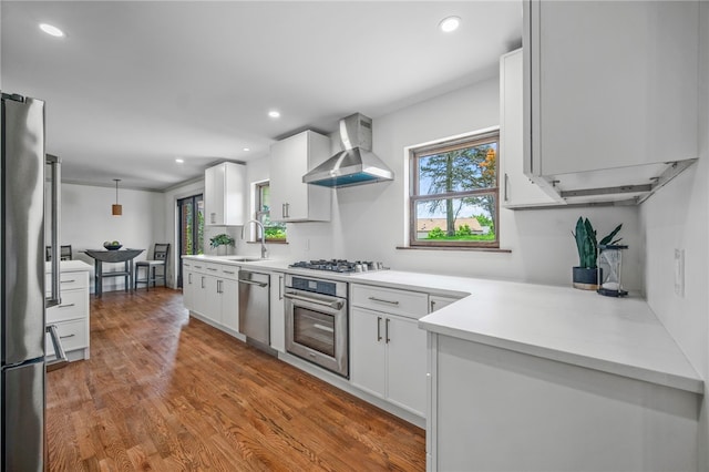 1202 Oakridge Rd, South Fayette, PA 15057 - kitchen featuring appliances with stainless steel finishes, wall chimney range hood, dark wood-style floors, light countertops, and white cabinetry