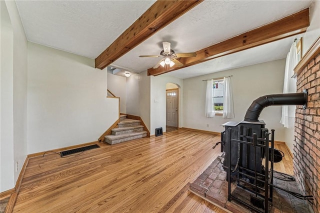 585 Dugan Way, New Kensington, PA 15068 - workout room with a wood stove, wood finished floors, arched walkways, ceiling fan, and a textured ceiling