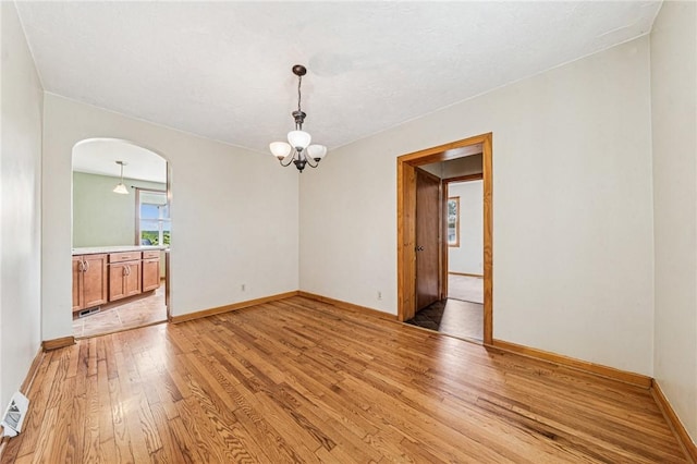 585 Dugan Way, New Kensington, PA 15068 - unfurnished room with light wood-style flooring, arched walkways, and a chandelier
