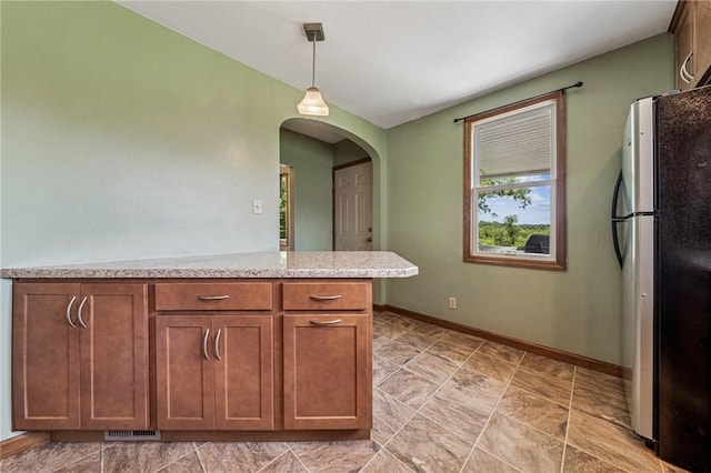 585 Dugan Way, New Kensington, PA 15068 - kitchen with freestanding refrigerator, arched walkways, pendant lighting, and brown cabinets