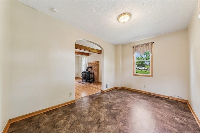 585 Dugan Way, New Kensington, PA 15068 - spare room with a wood stove, arched walkways, and a textured ceiling