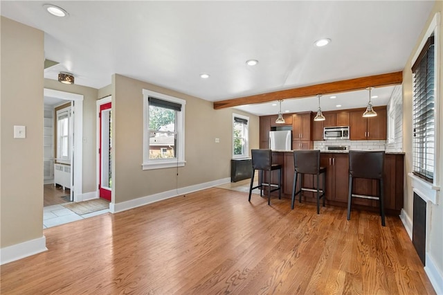 1216 Laclair Ave, Regent Square, PA 15218 - kitchen featuring stainless steel microwave, a peninsula, a kitchen bar, light wood finished floors, and radiator heating unit