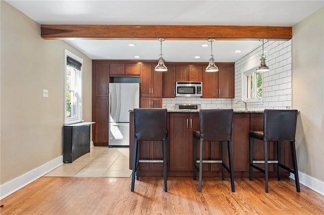 1216 Laclair Ave, Regent Square, PA 15218 - kitchen featuring stainless steel appliances, beam ceiling, tasteful backsplash, a kitchen bar, and light wood-style floors