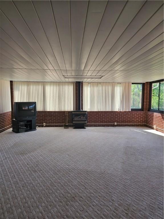 46 Corbett Ave, Hempfield Twp Wml, PA 15642 - carpeted empty room featuring a wood stove and brick wall